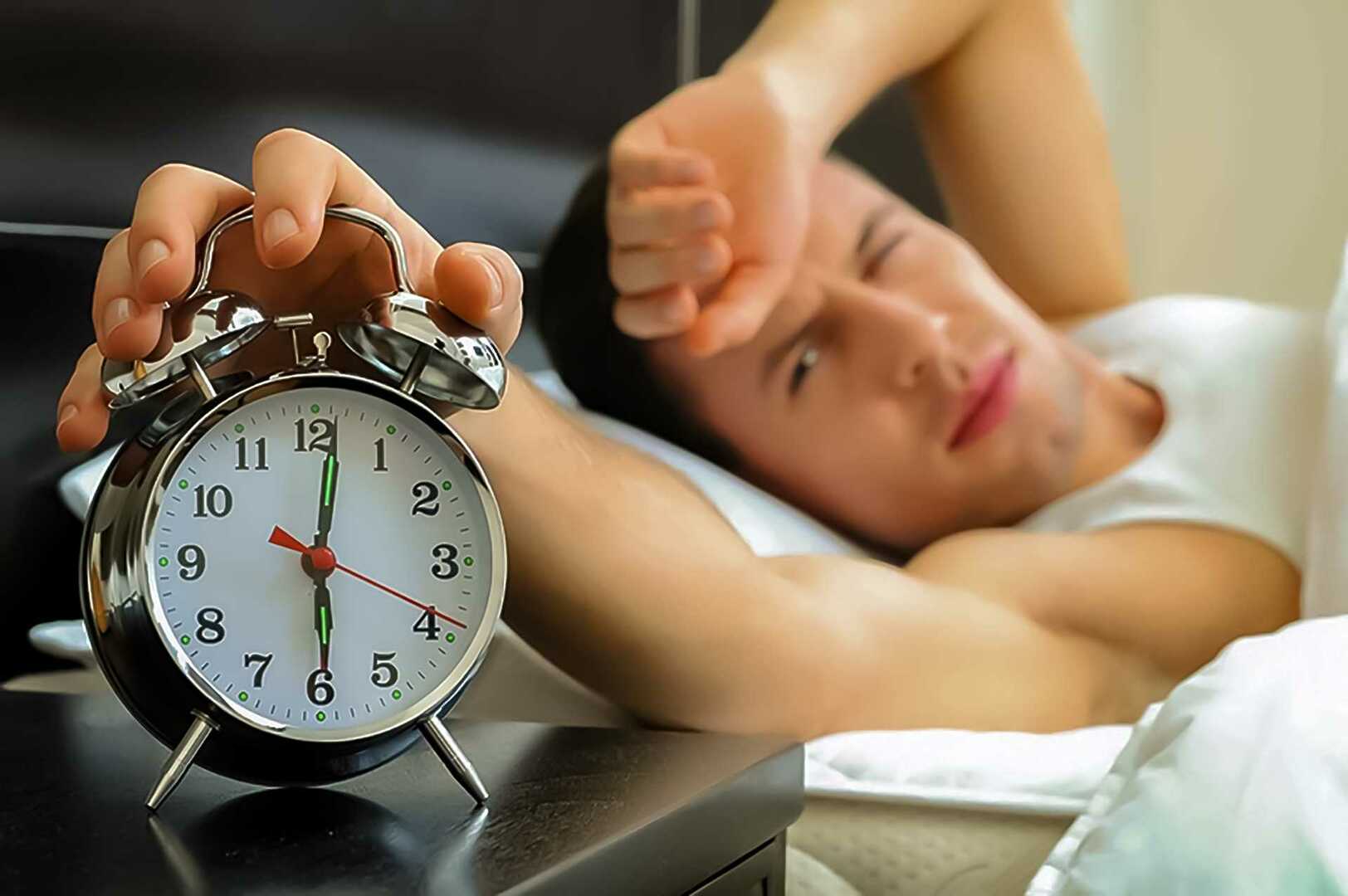 Человек спит с будильником